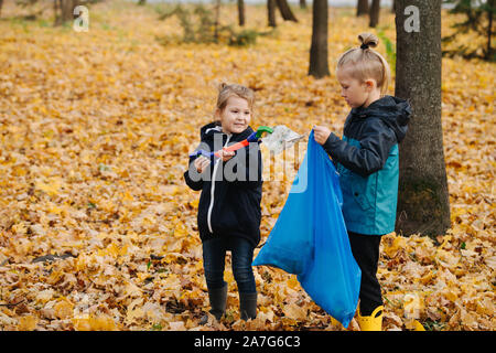 Petit enfant de mêmes parents recueillir à l'aide de détritus-déchets dans une forêt à l'automne Banque D'Images