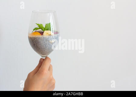 Jeune fille tenant un verre de chia pudding à la noix de coco d'aliments sains avec banane, mangue et fruit du dragon dans ses mains. Concept sain Banque D'Images