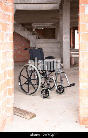 Un fauteuil roulant isolé dans une maison en construction derrière une porte. Concept de l'accessibilité Banque D'Images