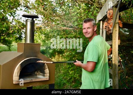 Man cooking pizza artisanale à l'extérieur dans un four au feu de bois Forno Bravo, fabriqué avec des ingrédients biologiques de Auberge Le Serendipity, In Browntown, Wisconsin, États-Unis Banque D'Images