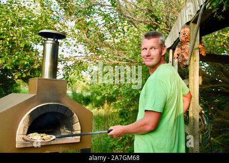 Man cooking pizza artisanale à l'extérieur dans un four au feu de bois Forno Bravo, fabriqué avec des ingrédients biologiques de Auberge Le Serendipity, In Browntown, Wisconsin, États-Unis Banque D'Images