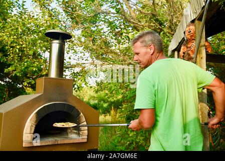 Man cooking pizza artisanale à l'extérieur dans un four au feu de bois Forno Bravo, fabriqué avec des ingrédients biologiques de Auberge Le Serendipity, In Browntown, Wisconsin, États-Unis Banque D'Images