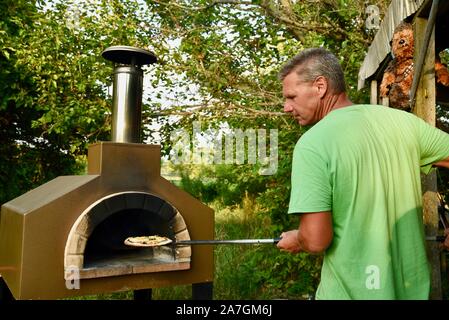 Man cooking pizza artisanale à l'extérieur dans un four au feu de bois Forno Bravo, fabriqué avec des ingrédients biologiques de Auberge Le Serendipity, In Browntown, Wisconsin, États-Unis Banque D'Images