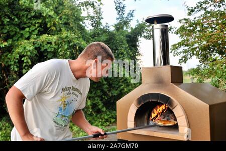 Man cooking pizza artisanale à l'extérieur dans un four au feu de bois Forno Bravo, fabriqué avec des ingrédients biologiques de Auberge Le Serendipity, In Browntown, Wisconsin, États-Unis Banque D'Images