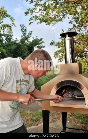 Man cooking pizza artisanale à l'extérieur dans un four au feu de bois Forno Bravo, fabriqué avec des ingrédients biologiques de Auberge Le Serendipity, In Browntown, Wisconsin, États-Unis Banque D'Images