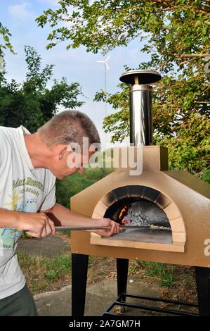 Man cooking pizza artisanale à l'extérieur dans un four au feu de bois Forno Bravo, fabriqué avec des ingrédients biologiques de Auberge Le Serendipity, In Browntown, Wisconsin, États-Unis Banque D'Images