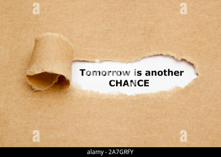 Citation de motivation demain est une autre chance apparaissant à travers un trou dans le papier marron déchiré. Banque D'Images