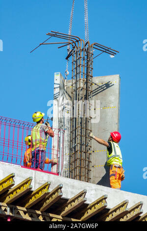 Trois travailleurs de la construction sont précisément régler le bloc de béton par grue Banque D'Images
