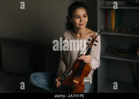 Jeune femme posant avec un violon à la maison Banque D'Images