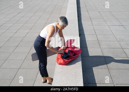 Femme d'âge moyen d'emballer de yoga par ocean Banque D'Images