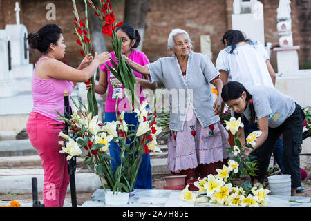 Une famille mexicaine décore la tombe de la famille pour le jour de la fête des morts connus en espagnol comme día de muertos à l'ancien cimetière le 31 octobre 2013, au Mexique. Xoxocotlan dans Le festival célèbre la vie de ceux qui sont morts. Banque D'Images