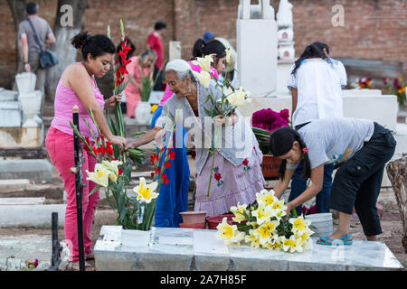 Une famille mexicaine décore la tombe de la famille pour le jour de la fête des morts connus en espagnol comme día de muertos à l'ancien cimetière le 31 octobre 2013, au Mexique. Xoxocotlan dans Le festival célèbre la vie de ceux qui sont morts. Banque D'Images