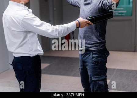 Protection avec un détecteur de métal contrôler un homme d'armes et objets de métal avant d'entrer dans le ministère du trésor Banque D'Images