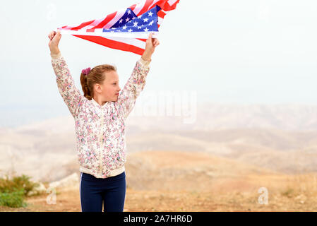 Drapeau américain. Petite fille heureuse patriotique avec drapeau américain sur fond de plein air de la nature. USA célébrer le 4 juillet. Banque D'Images