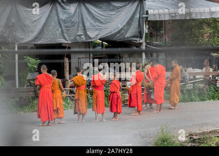 Moines en robes orange recueillir les dons de nourriture le matin. Moines dans les rues de la ville de Pakse, Laos. Banque D'Images