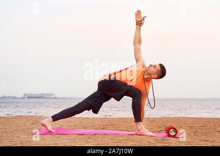 Athletic man doing yoga asanas dans la nature, la mer de sable Banque D'Images