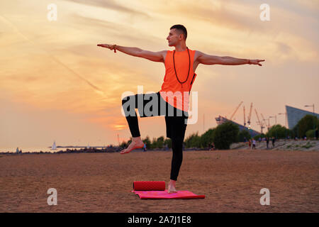 Athletic man doing yoga asanas dans la nature, la mer de sable Banque D'Images