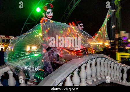 Les ailes au-dessus de l'eau LED Wispy affichent une silhouette élégante lors du festival Day of the Dead, en novembre, le mois d'accueil de la Journée des morts au Mexique. Southport Pleasureland a mis en scène sa propre tournure sur la célébration mexicaine effrayante avec une cascade explosive de couleurs et de motifs créés tout en dansant avec lumière, lumineux, numérique, design en boucle, mouvement, motif et réjouissances vibrantes dans un festin pour les sens. Une foule de divertissements et de célébrations fantastiques ont amené des milliers de touristes à la station pour profiter du spectacle. Banque D'Images