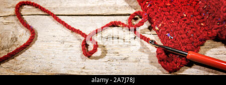 Crochet, bannière et foulard rouge sur la table en bois, travail manuel et de la mode Banque D'Images