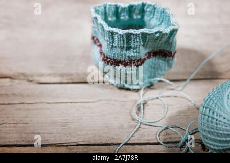 Ouvrage crocheté, chauffe-tasse bleu et balle de laine sur fond de bois Banque D'Images