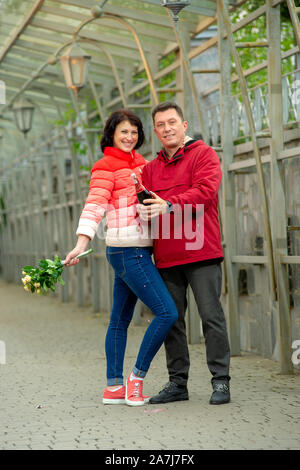 Couple avec un bouquet de fleurs et champagne. D'âge mûr avec un bouquet de fleurs. Banque D'Images