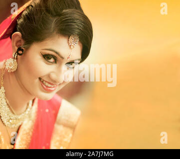 Superbe mariée Indiens vêtus de vêtements de mariage hindou traditionnel sari rouge brodée d'or Bijoux et un voile tendre sourire avec copie supplémentaire spa Banque D'Images