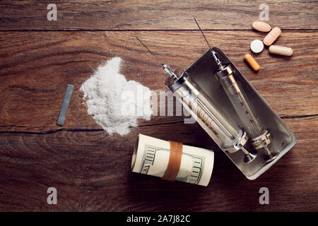 Vintage seringues, cocaïne, pills and rolled dollar bills sur table en bois. Concept de la toxicomanie et du trafic. Banque D'Images