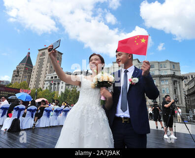 Un couple de prendre des photos d'eux-mêmes par le fleuve Huangpu à Shanghai, Chine, 19 septembre 2019. 15 couples au groupe par le mariage du fleuve Huangpu Banque D'Images