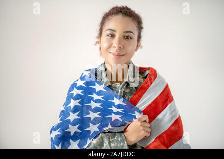 Belle jeune femme militaire patriotique holding American flag Banque D'Images