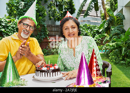 Heureux vieux couple celebrating birthday et de bébés-cour de leur maison à Banque D'Images