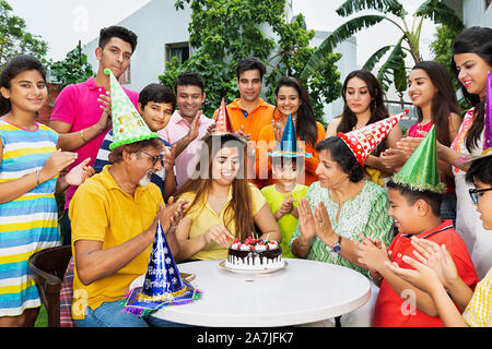 Grand groupe de membres de la famille indienne célébrant un anniversaire fille adultes-en-cour de leur maison Banque D'Images