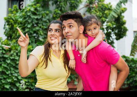 Heureux père de famille indienne portant sa petite fille sur-piggyback avec Mère Doigt quelque part en-extérieur au-park Banque D'Images