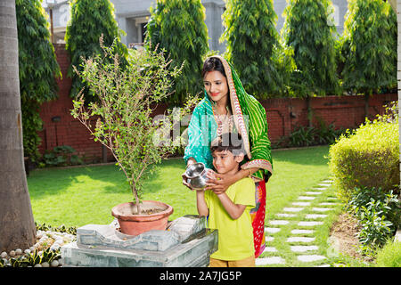 Indian hindu mère et petit-fils de l'eau saint-plante Tulsi Performing Puja en-cour de leur maison à Banque D'Images