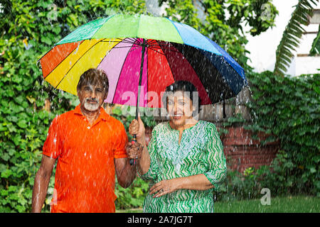 Happy Romantic Couple de personnes âgées dans le cadre de la pluie de printemps dans le jardin Banque D'Images