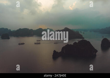 Vue aérienne de la Baie d'Ha Long au Vietnam pendant un beau coucher avec calme, mer tranquille et bon nombre des nouveaux navires de croisière de luxe dans la baie Banque D'Images