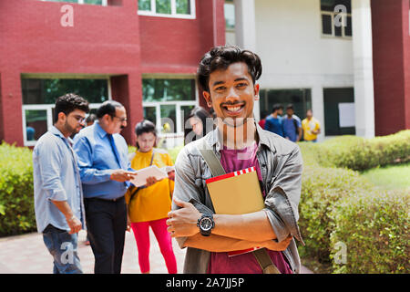 Young male College Student Holding Book avec les étudiants et le professeur In-Outside Bâtiment du campus Banque D'Images