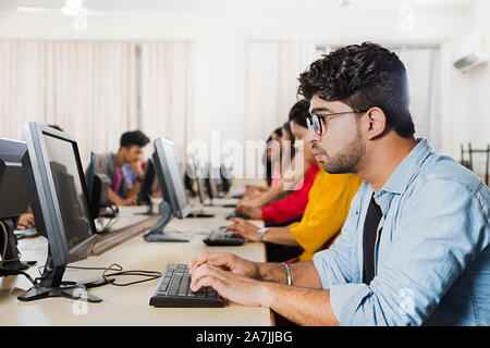 Jeune homme choqué College student studying Looking-At écran Ordinateur Badnews E-Learning in Computer Lab Banque D'Images