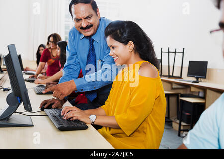 Professeur de collège indien fille aider avec l'ordinateur Étudiant Étudiant leçon pointing at Computer Class Banque D'Images