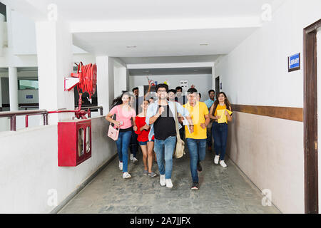 Groupe d'amis étudiants courir vite At-Campus Corridor s'Amusant Joyeux Banque D'Images