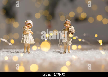 Sur le thème de Noël Décoration figurines. Statuette garçon et fille avec un bouquet de fleurs. Décoration d'arbre de Noël. Décor de fête, chaud bokeh lights Banque D'Images