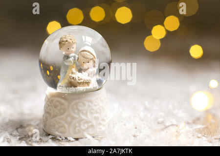 Sur le thème de Noël Décoration figurines. Une bille de verre avec des flocons de neige dans laquelle deux hommes se penchent sur le berceau, un symbole de la Nativité du Christ. Ch Banque D'Images