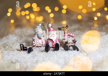 Figurines décoratives d'un thème de Noël. Ensemble de statuettes de santa, bonhomme de neige et les cerfs. Décoration d'arbre de Noël. Décor de fête, chaud bokeh lights Banque D'Images