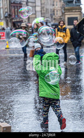 Edinburgh, Ecosse, Royaume-Uni. 29Th sep 2019. Sur la photo : les touristes à Édimbourg ignorer la forte pluie et chase une fois que les bulles créées par un artiste de rue sur le Royal Mile. Credit : Riche de Dyson/Alamy Live News Banque D'Images