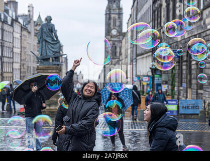 Edinburgh, Ecosse, Royaume-Uni. 29Th sep 2019. Sur la photo : les touristes à Édimbourg ignorer la forte pluie et chase une fois que les bulles créées par un artiste de rue sur le Royal Mile. Credit : Riche de Dyson/Alamy Live News Banque D'Images