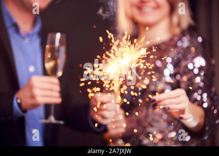 Photo de couple avec verres de champagne et cierges sur fond noir en studio Banque D'Images