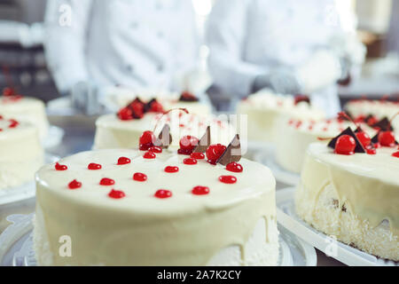 Cerise rouge sur blanc gâteau sur une table avec des gâteaux Banque D'Images