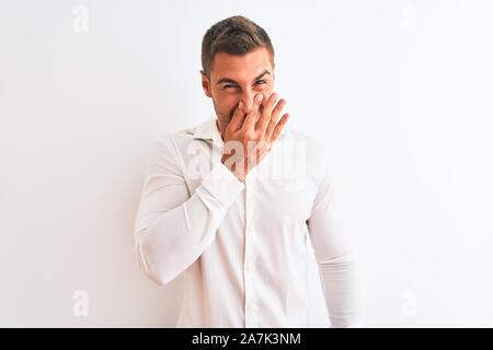 Beau jeune homme d'affaires portant shirt sur fond isolé humer un stinky et dégoûtant, odeur insupportable, apnée Banque D'Images