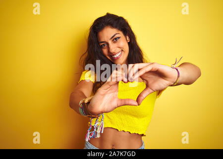 Belle Jeune femme portant des T-shirt sur fond jaune isolé permanent smiling in love montrant le symbole de coeur et la forme des mains. Roman Banque D'Images