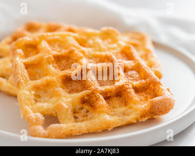 Gaufres salées parfait keto. Deux ingrédients chaffles sur plaque sur fond de marbre blanc. Les œufs et le fromage parmesan bas carb gaufres. Extreme close up view. Banque D'Images