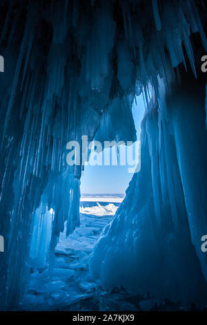 Vue depuis une grotte de glace avec d'énormes glaçons bleus sur le Lac Baïkal. Stalactites de cristal au plafond. Beaucoup de glace cassée à l'extérieur de la grotte. Banque D'Images